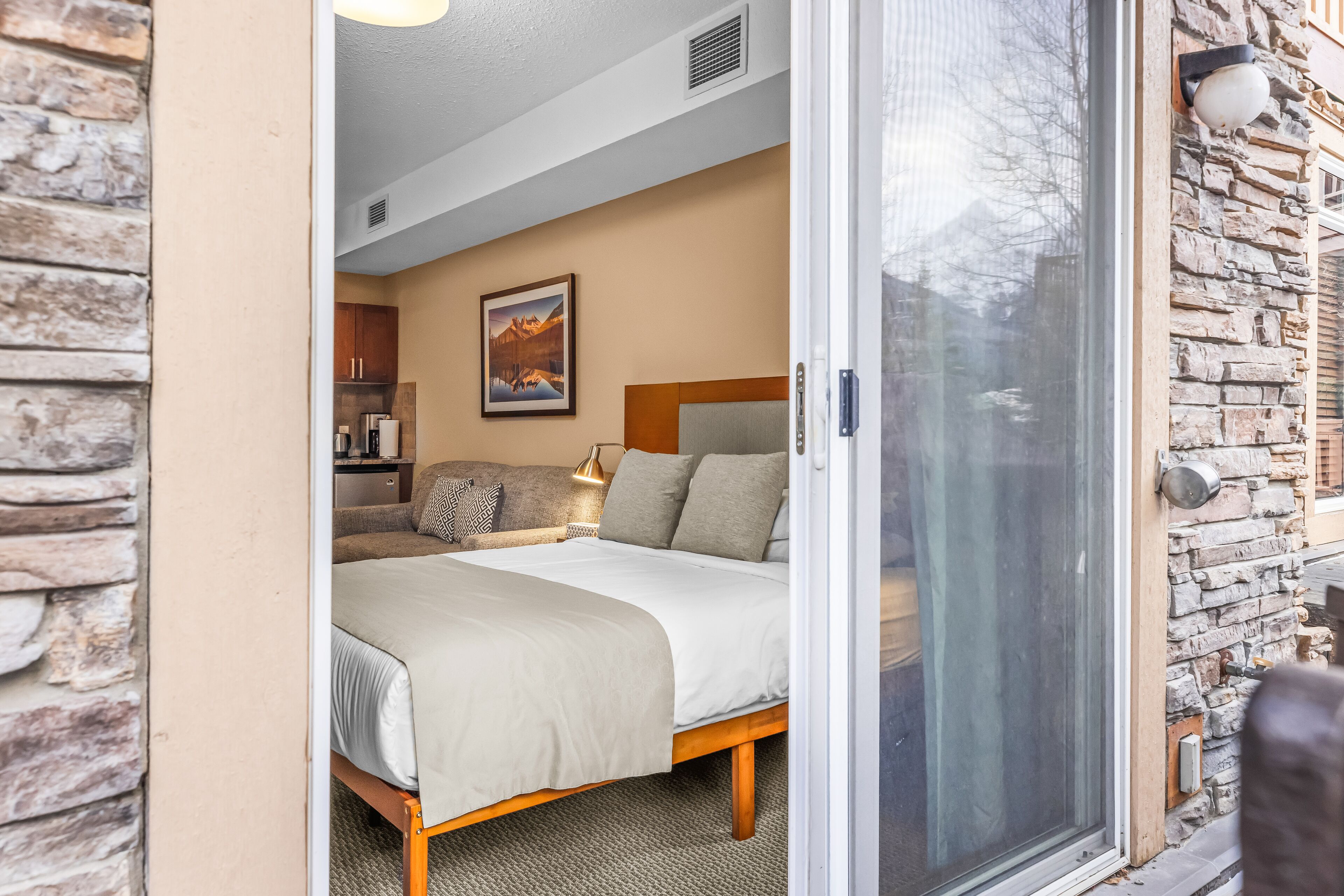 A bedroom with a bed, a nightstand, a lamp, and a painting on the wall.