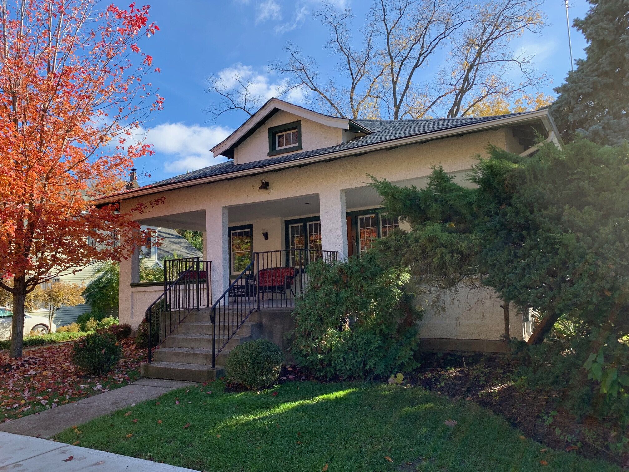 A two-story house with a covered porch, a front staircase, and a well-maintained lawn.