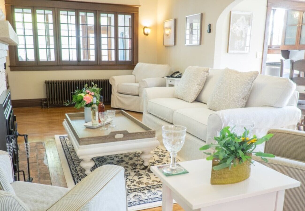 Un salon chaleureux avec un canapé blanc, une table basse et une petite table d’appoint sur laquelle est posé un vase de fleurs.