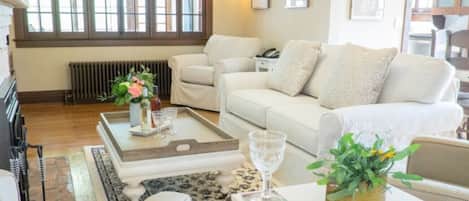 A cozy living room with a white sofa, a coffee table, and a small side table with a vase of flowers.