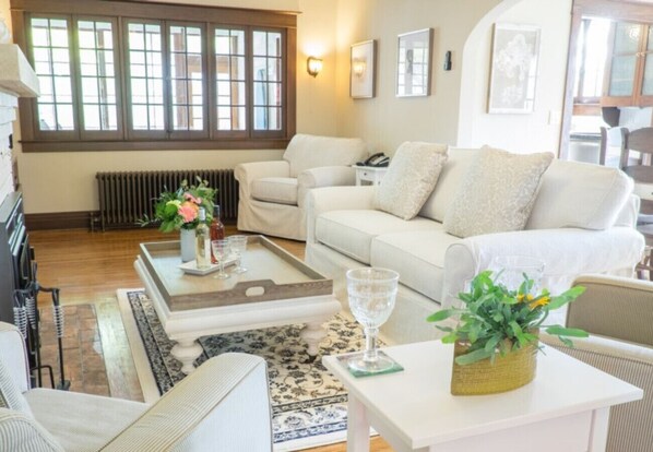 A cozy living room with a white sofa, a coffee table, and a small side table with a vase of flowers.