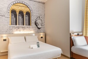 Una habitación de hotel con una cama grande, una pared de ladrillo con un arco decorativo y un cabecero con iluminación integrada.
