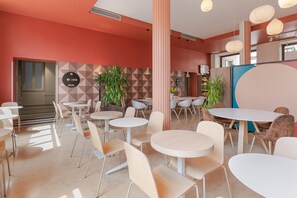 A modern interior with round tables and chairs, a geometric patterned wall, and a staircase leading to another level. - B&B Hotel Treviso (Treviso)
