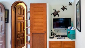 Ein Flur mit Holztüren, einem Fernseher auf einem Regal und Wandbildern mit Schildkrötenmotiven.