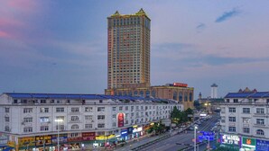 A multi-story hotel with a prominent central tower, a row of shops along the street, and a clear view of the road.
