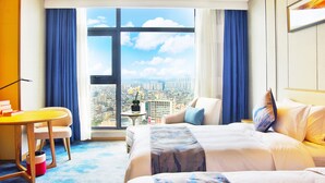 A hotel room with a large window, a bed, a desk, and a chair.