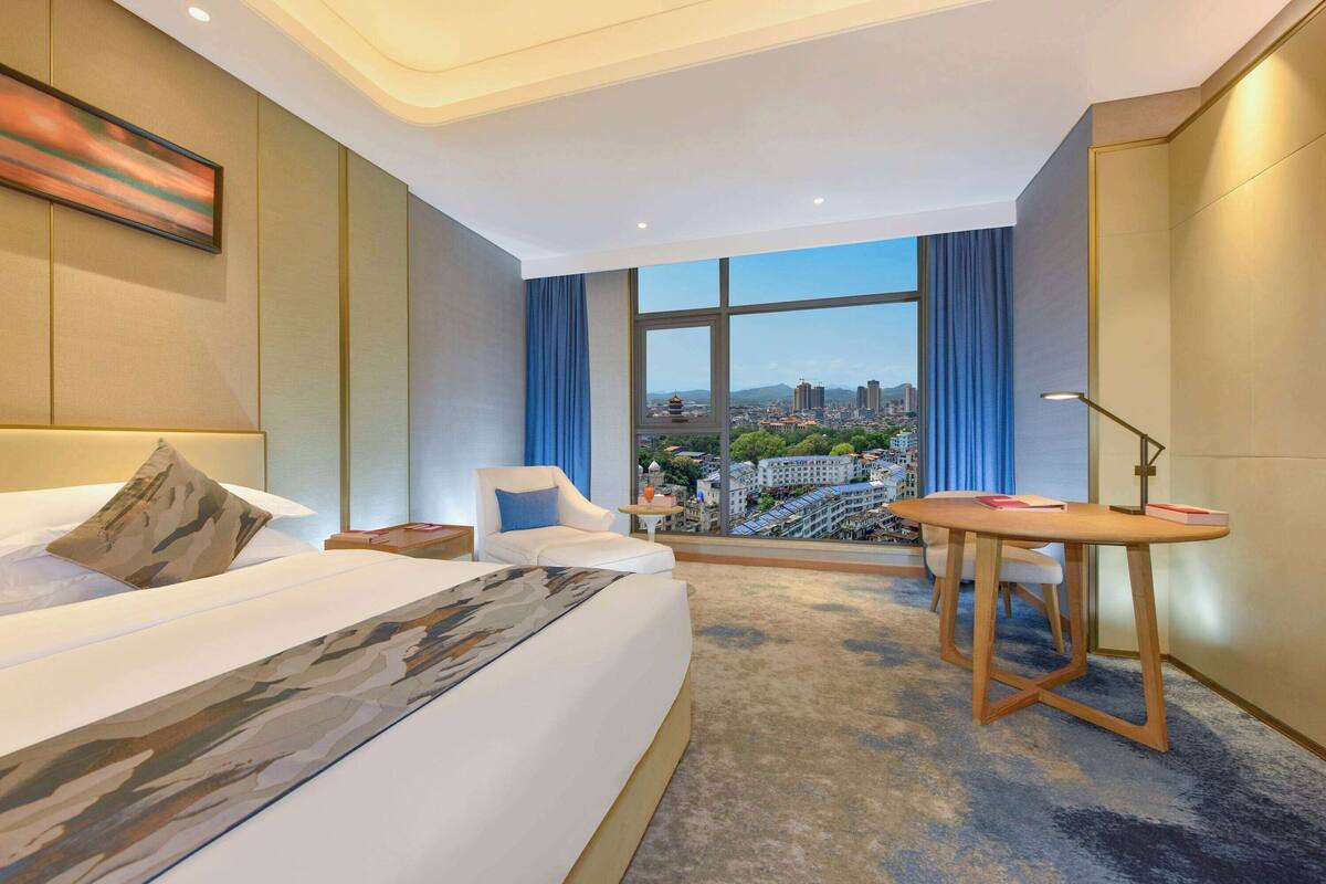Une chambre d’hôtel avec un grand lit, un bureau et une vue sur la ville.