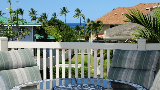 A balcony with a view of the ocean, surrounded by palm trees and a white fence. - Beautiful Townhome with Exquisite Furnishings.  Garage available for guest use. (Kailua - Kona)