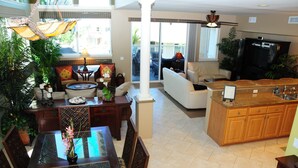 A spacious living area with a dining table, chairs, a sofa, and a kitchen area with a countertop and cabinets. - Beautiful Townhome with Exquisite Furnishings.  Garage available for guest use. (Kailua - Kona)