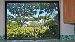 A kitchen with a large window, a stainless steel sink, and a tiled backsplash. - Ekahi 36a, 1BR 2BA condo, Sleeps 4 (2 Adults + 2 Kids) (Wailea-Makena)