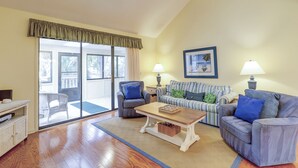 A living room with a sliding glass door leading to a balcony, a ceiling fan, and two lamps on side tables.