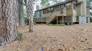 A two-story house with a wooden deck and a staircase leading to the second floor.