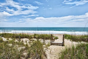 Ein Strand mit einer hölzernen Bank und einer Holzkonstruktion, wahrscheinlich ein Rettungsschwimmerstand, im Sand.