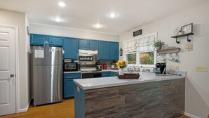 Een moderne keuken met blauwe kastjes, een roestvrijstalen koelkast en een centraal kookeiland.