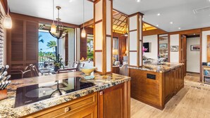 A kitchen with wooden cabinets, granite countertops, and a central island. - Top-Floor breathtaking views, close to beach! (Kamuela)