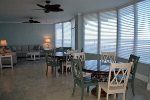 A dining area with a round table and chairs, a sofa, and a ceiling fan. - Updated Direct Oceanfront - 3 bedroom #1007; Beach Access and Heated Pool (Daytona Beach Shores)