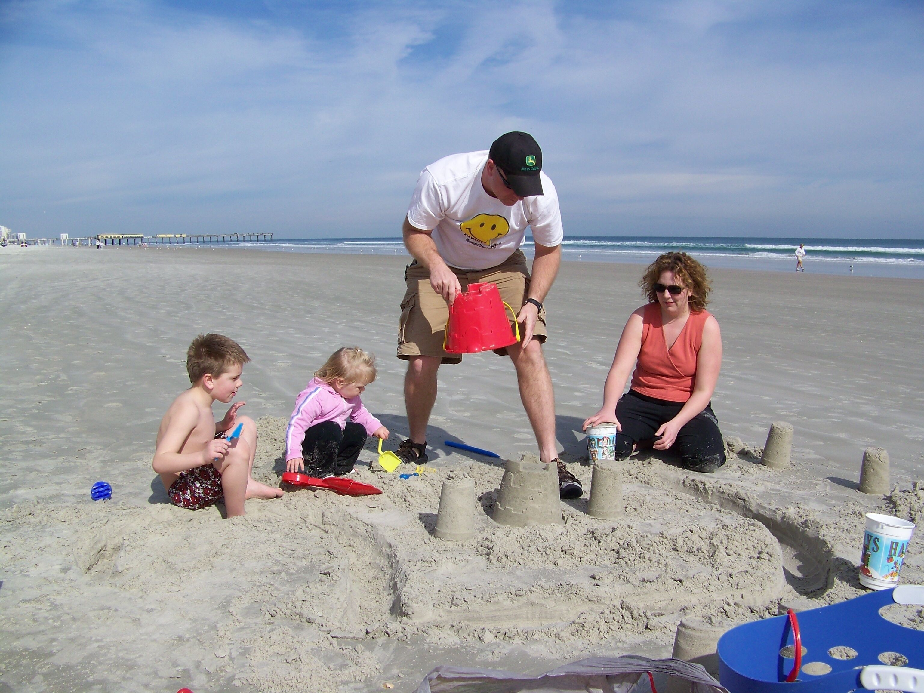 Ein Sandstrand, auf dem Menschen Sandburgen bauen.