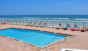 A swimming pool with a view of the ocean, beach chairs, and umbrellas. - Updated Direct Oceanfront - 3 bedroom #1007; Beach Access and Heated Pool (Daytona Beach Shores)