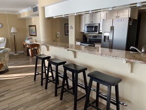 A modern kitchen with a bar area, stainless steel appliances, and a wooden floor. - Updated Direct Oceanfront - 3 bedroom #1007; Beach Access and Heated Pool (Daytona Beach Shores)