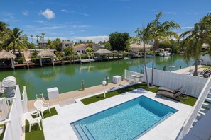 Una piscina con vistas a un puerto deportivo y casas al fondo.