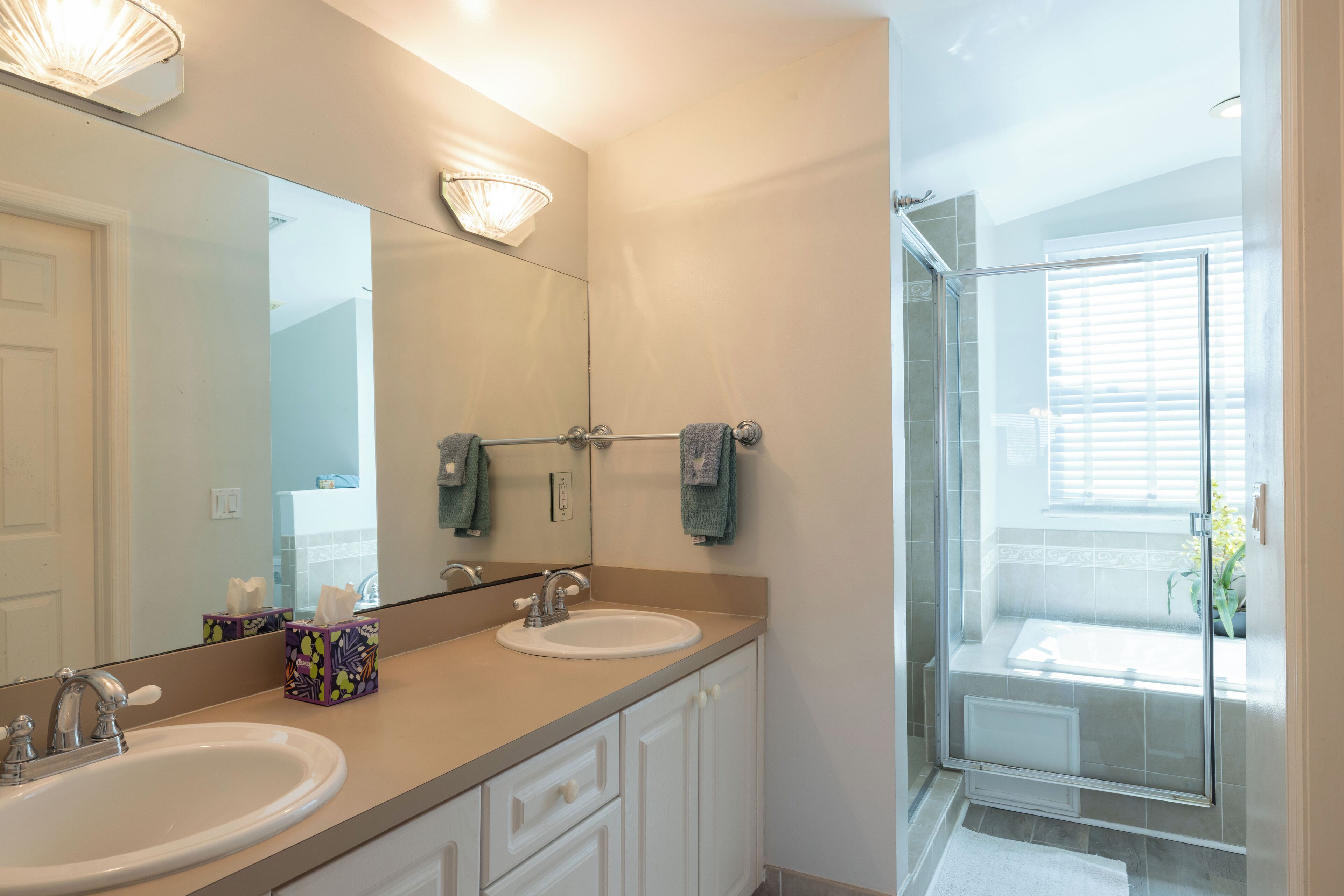 A bathroom with two sinks, a large mirror, and a glass shower enclosure.