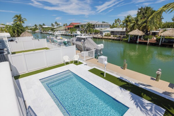 Une piscine avec vue sur un port de plaisance et des maisons en arrière-plan.