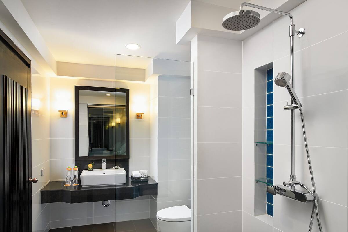 Ein modernes Badezimmer mit Duschkabine aus Glas, einer weißen Toilette und einem Waschbecken mit Spiegel darüber.