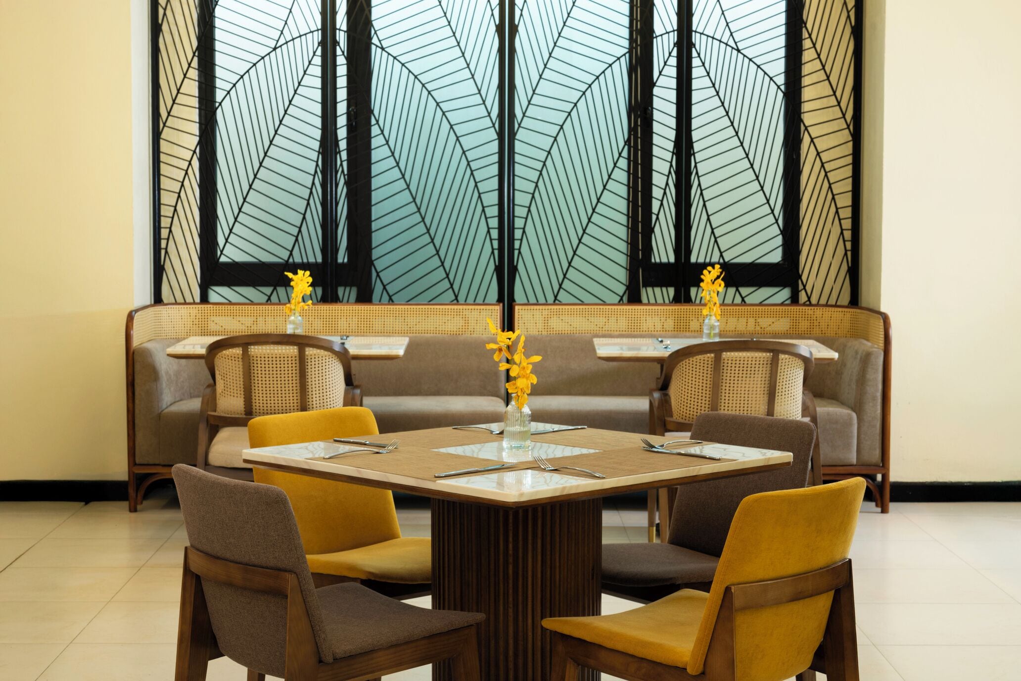 A dining area with a table set for four, surrounded by chairs, with a decorative vase on the table.
