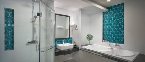 Un baño moderno con cabina de ducha de vidrio, lavamanos blanco y un espejo grande.