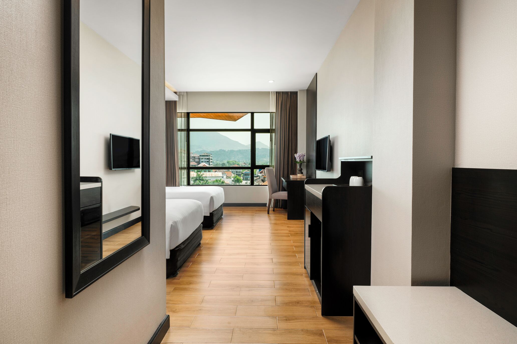 Habitación de hotel con cama, escritorio, televisor y ventana grande con vistas.