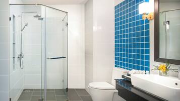 A modern bathroom with a glass-enclosed shower, a white toilet, and a sink with a blue-tiled backsplash.