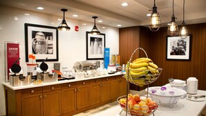 A hotel breakfast area with a buffet setup, including fruits, a coffee station, and a juice dispenser. - Hampton Inn Lebanon (Lebanon)