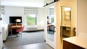 A hotel room with a desk, chair, TV, and a view of greenery through the window. - Hampton Inn Lebanon (Lebanon)