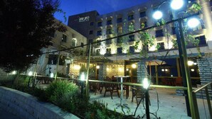 A hotel with outdoor seating, a stone facade, and multiple balconies. - Canaan Spa Hotel (Safed)