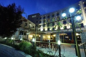 Un hotel con terraza al aire libre, fachada de piedra y varios balcones.