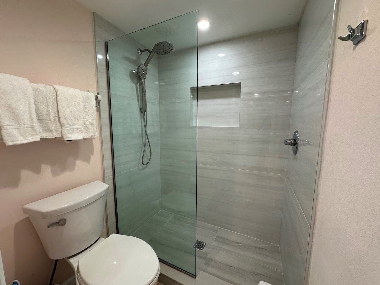 Ein modernes Badezimmer mit einer Glaskabine zur Dusche, einer weißen Toilette und einer Glastrennwand.