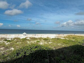 Uma praia com uma tenda branca e vista clara do oceano.