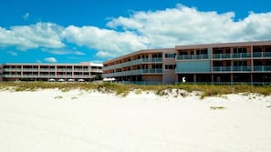 A beachfront hotel with multiple floors, balconies, and a sandy beach in the foreground. - Anna Maria Island Club 12 - Condo 2 Bedroom/ 2 Bath beach view, maximum occupancy of 4 people.  Community pool, Max 1 vehicle. (Bradenton Beach)