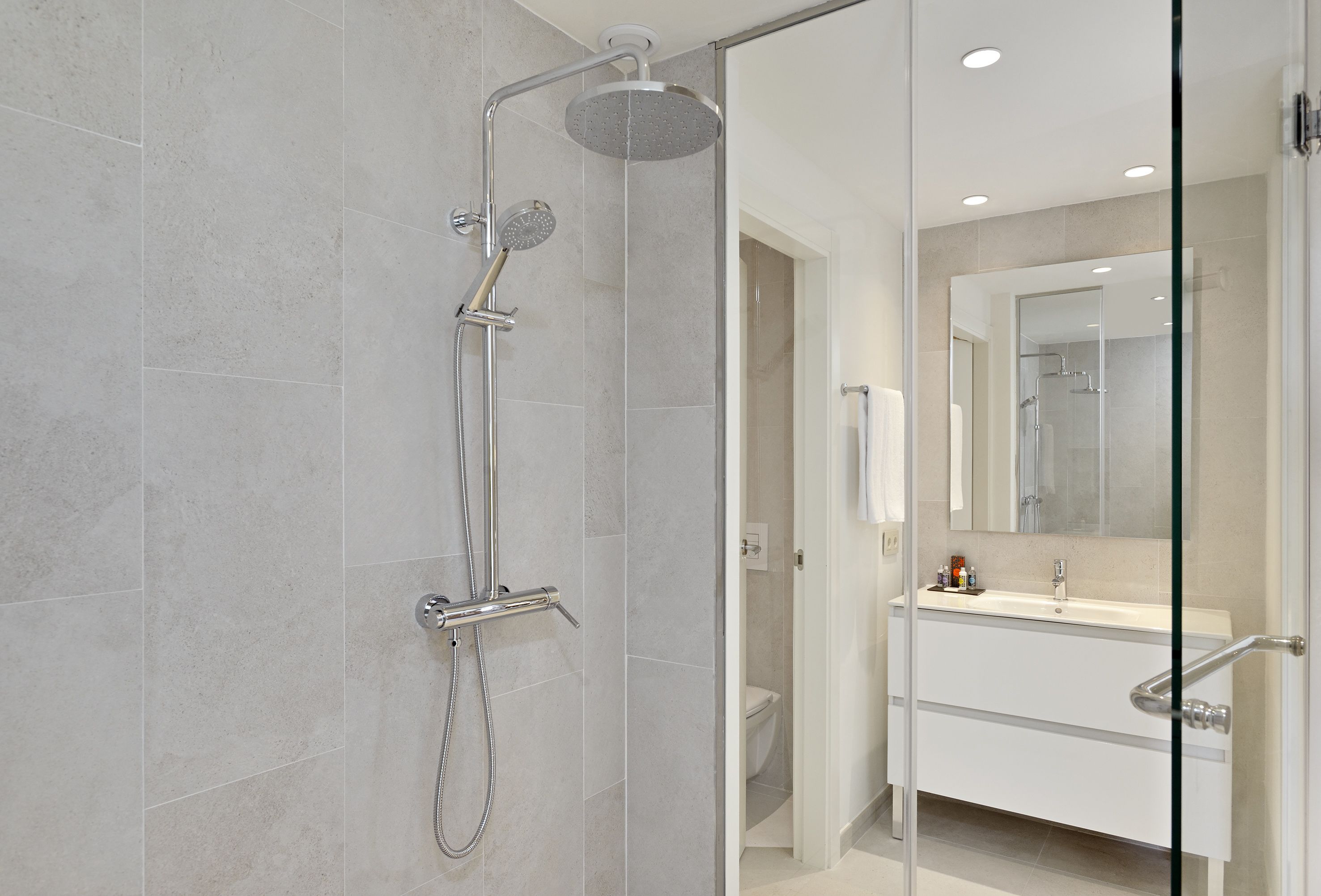 A modern bathroom with a glass-enclosed shower, a white sink, and a large mirror.