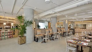 A modern restaurant with high ceilings, exposed ductwork, and a mix of seating including booths and tables. - INNSiDE by Meliá Calviá Beach (Calvia)