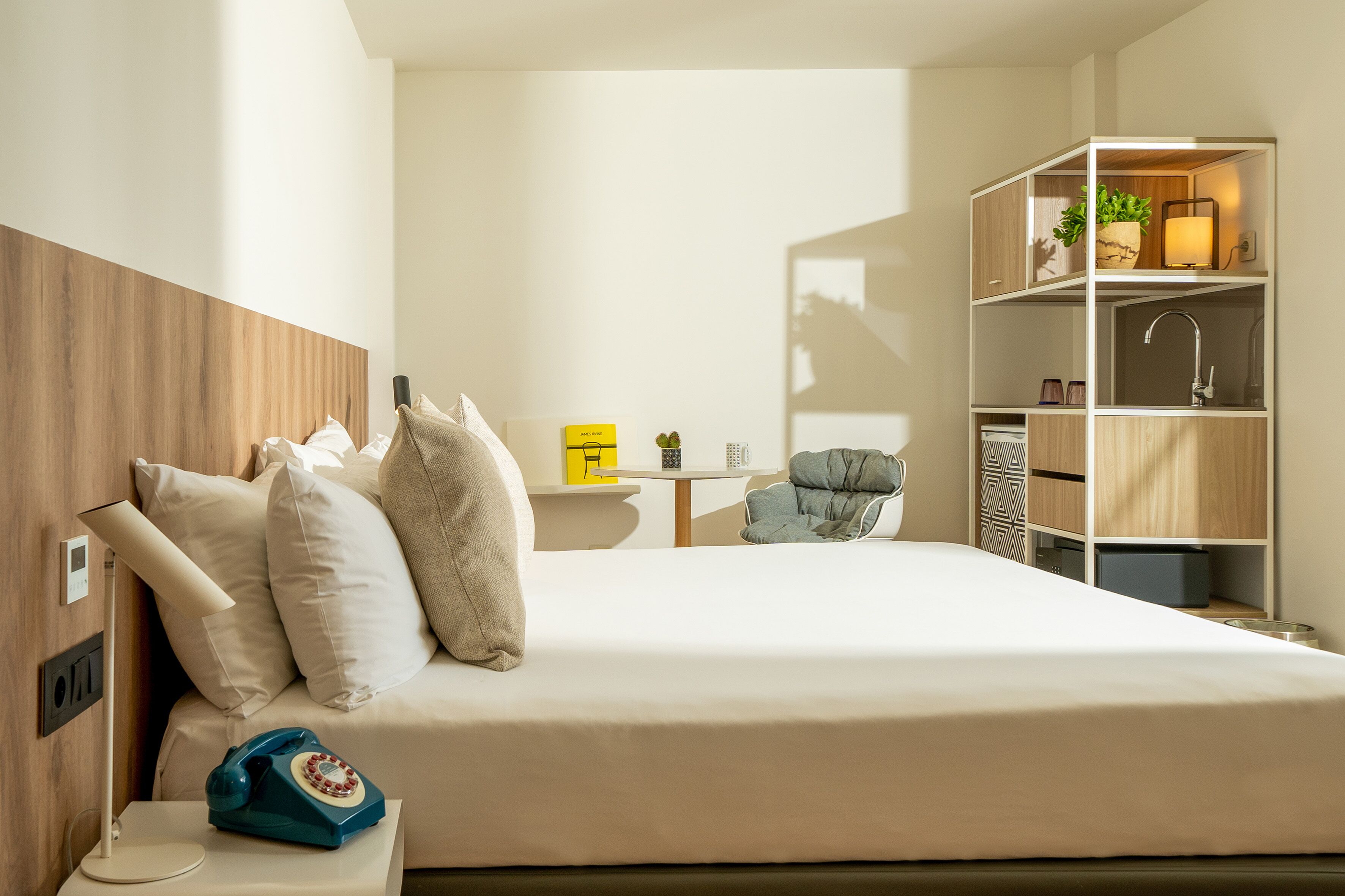 A hotel room with a bed, bedside table, lamp, and a built-in wardrobe.