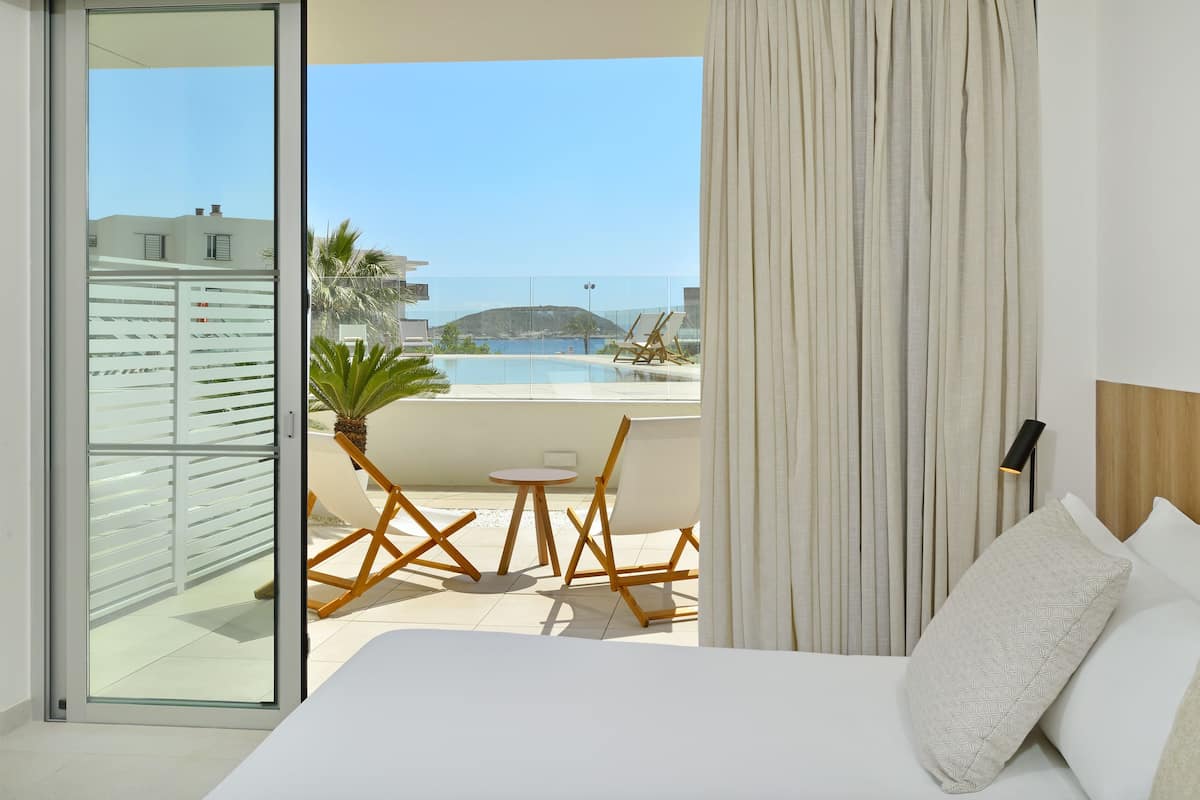 Une chambre d’hôtel avec un balcon, un lit, une petite table et une chaise.