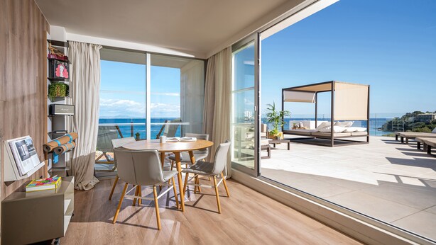 A modern living room with a large sliding glass door leading to a balcony with a view of the sea. - INNSiDE by Meliá Calviá Beach (Calvia)