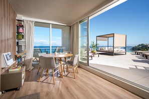 Een moderne woonkamer met een grote schuifpui naar een balkon met uitzicht op zee.