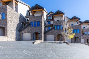 A row of modern multi-story houses with stone facades, large windows, and wooden balconies.