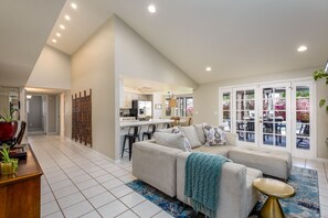 A spacious living area with a large sofa, a coffee table, and a dining area with a kitchen in the background. - Santa Barbara-Style Home in the Center of Scottsdale w/ private heated pool. (Scottsdale)