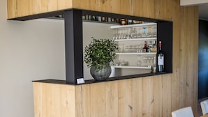 Un espace bar moderne avec un comptoir en bois, une plante en pot et une bouteille de vin.