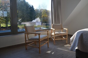 A room with two wooden chairs, a glass table, and a bed with a blanket. - Aquarand (Zemst)