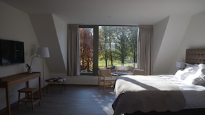 Une chambre à coucher comprenant un lit, un bureau, une chaise et une fenêtre donnant sur des arbres.