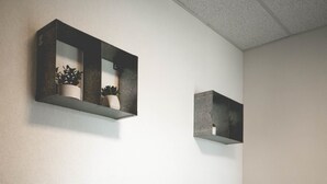 A modern living room with two sofas, a coffee table, and two wall-mounted shelves with potted plants. - Lakeside Inn (Clear Lake)